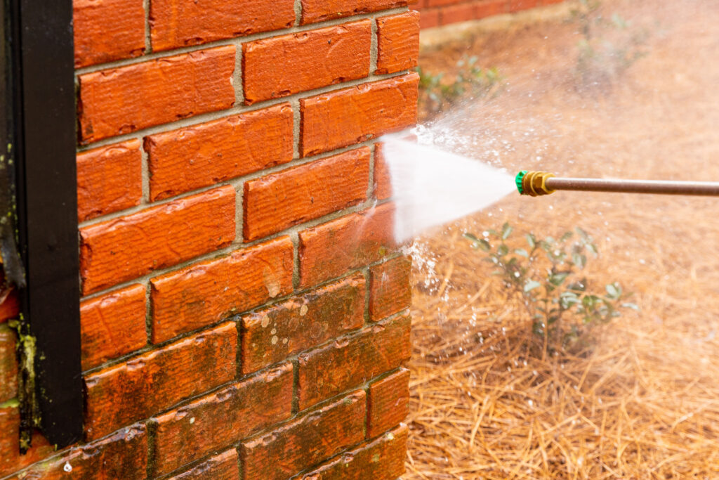 McNicol Landscapes power washing a brick wall.